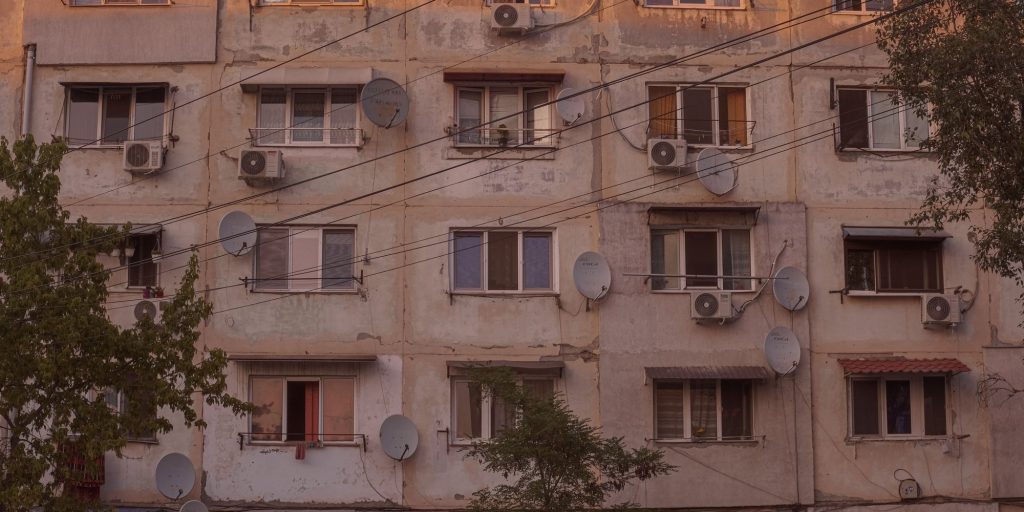An older urban apartment building with window air-conditioning units on its facade
