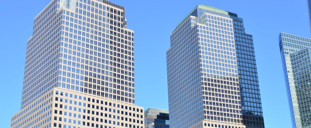 Glass office towers in a financial district photographed from street level against the sky