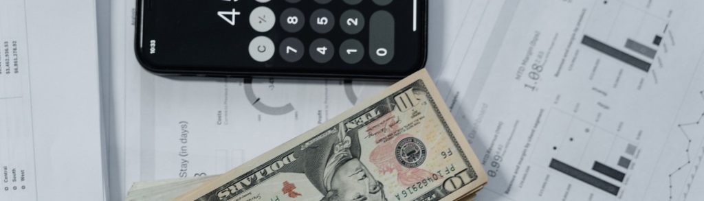 A calculator, cash and financial documents laid out on a desk