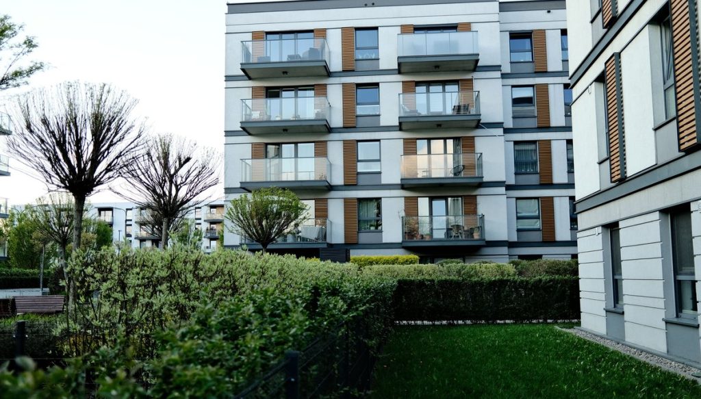 A modern apartment complex with tiered balconies and planted grounds