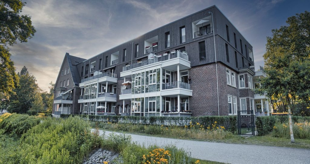 A modern low-rise apartment building surrounded by mature trees