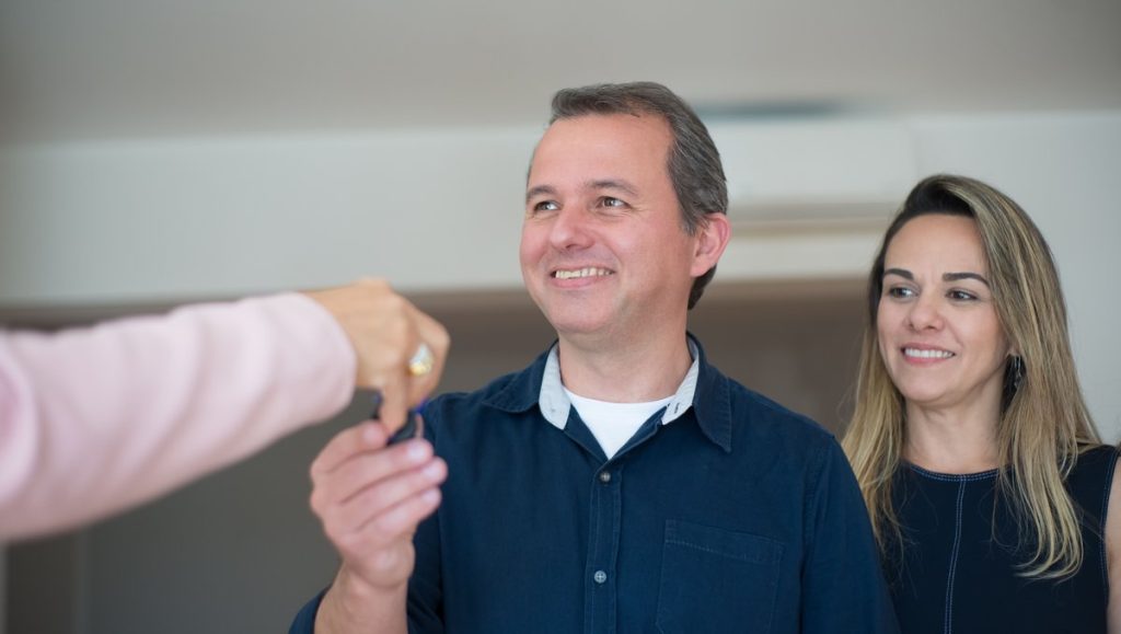 A couple being handed the keys to a property indoors
